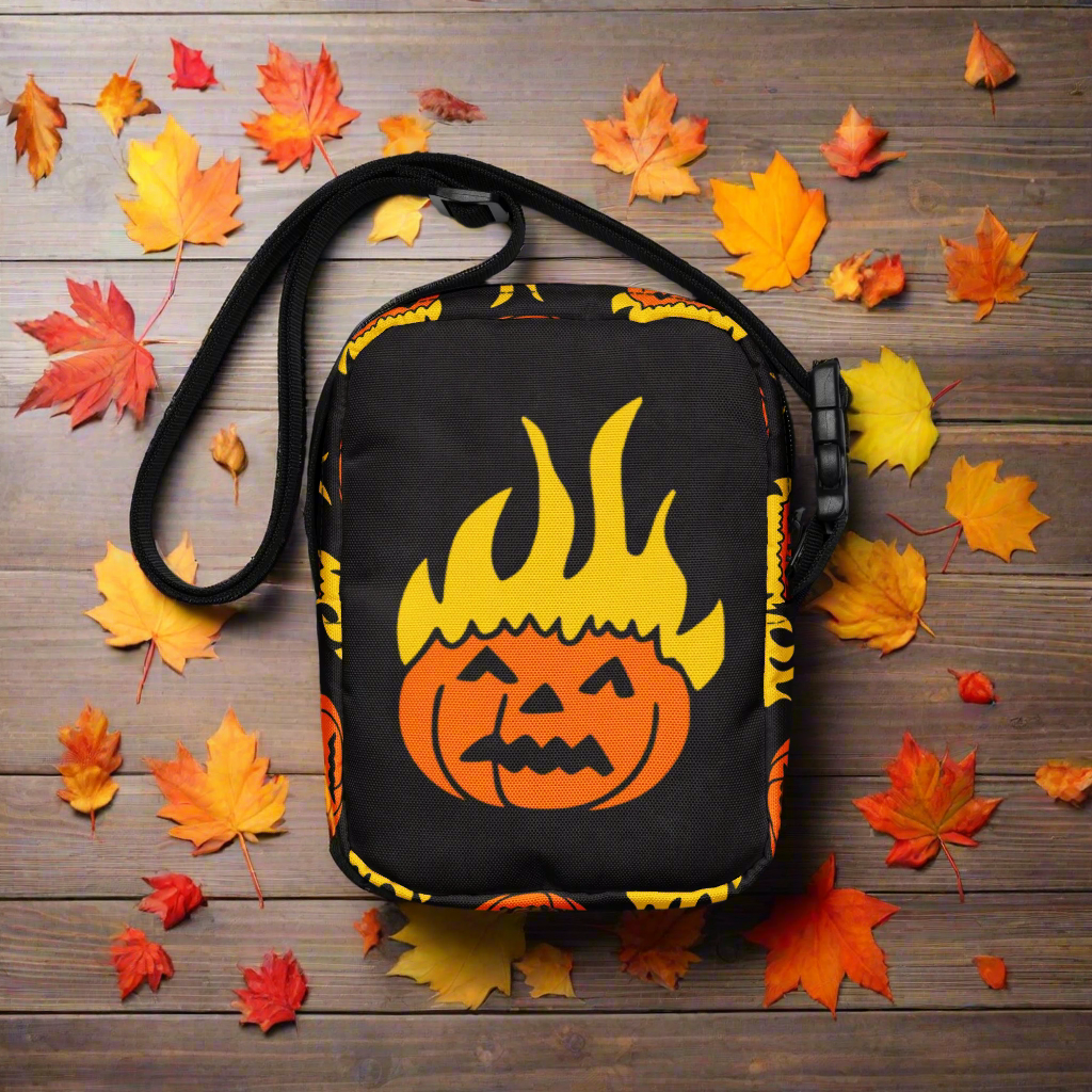 Black crossbody bag with orange pumpkin design and flames on a white background