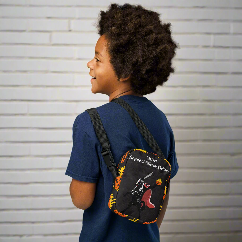 Child wearing a blue shirt with a black bag featuring colorful designs on a white background