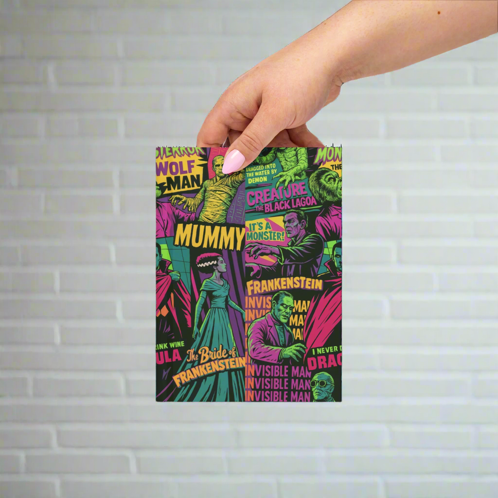 Hand holding a notebook with classic monster movie characters on the cover