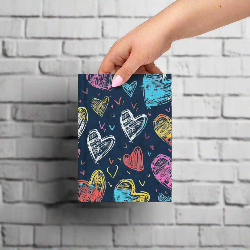 Notebook with colorful heart pattern held by a hand on a white background